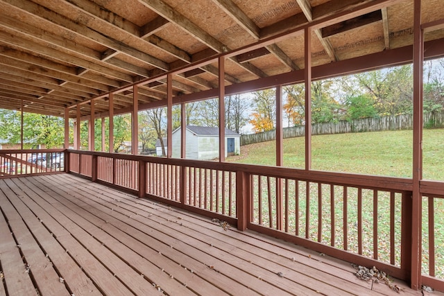 wooden terrace featuring a lawn and a storage shed