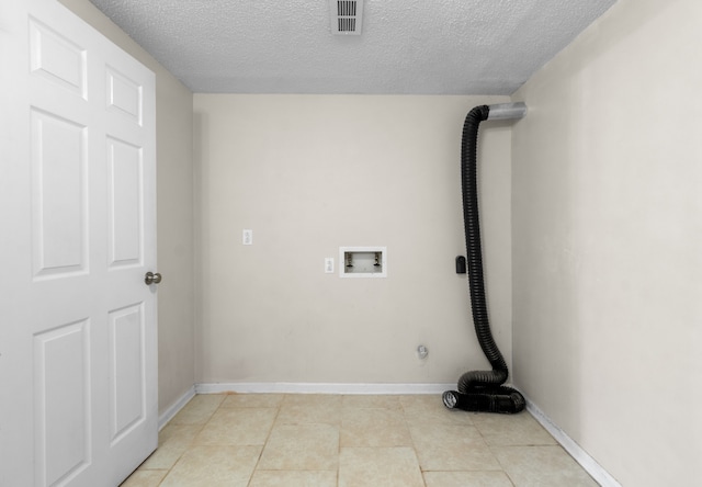 clothes washing area featuring a textured ceiling, washer hookup, and light tile patterned floors