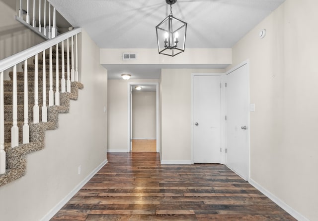 foyer featuring dark hardwood / wood-style flooring, a chandelier, and a textured ceiling