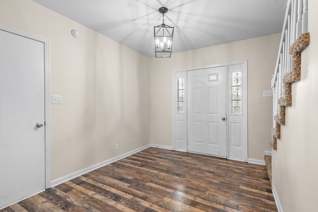 entryway featuring a textured ceiling, dark hardwood / wood-style floors, and a chandelier