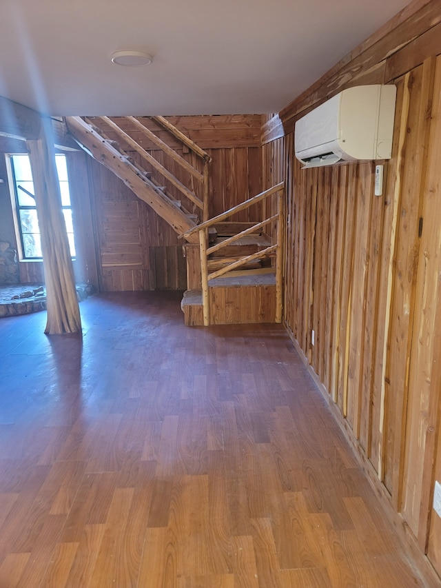 interior space with wood walls, hardwood / wood-style flooring, and an AC wall unit