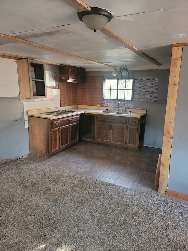 kitchen with white gas stovetop, sink, dark tile patterned floors, and tasteful backsplash