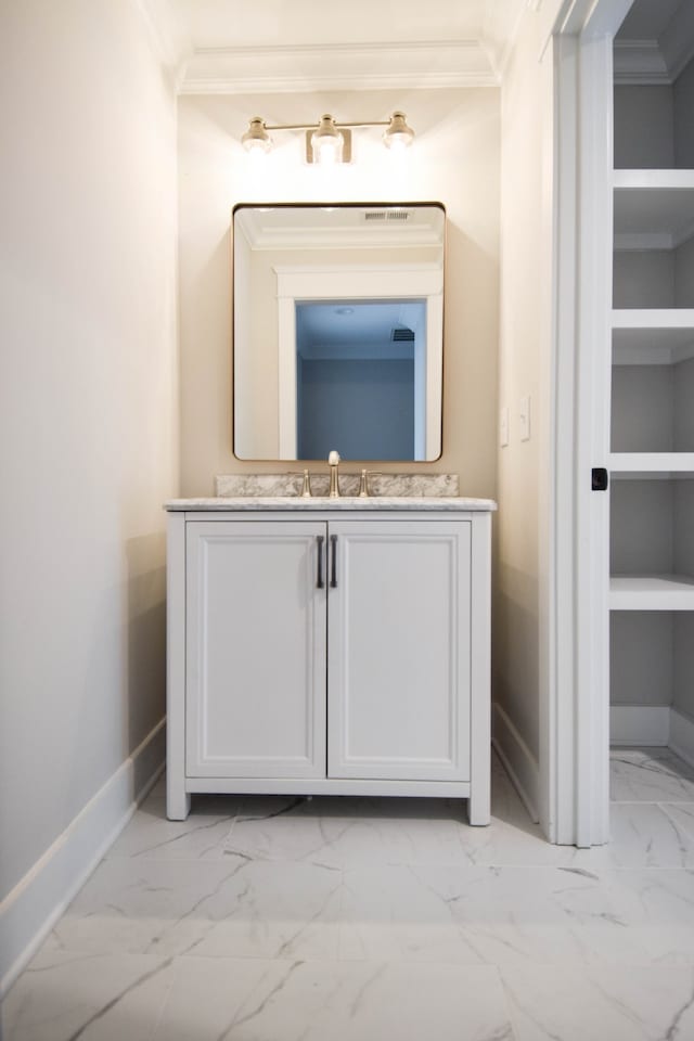 bathroom with marble finish floor, ornamental molding, and baseboards