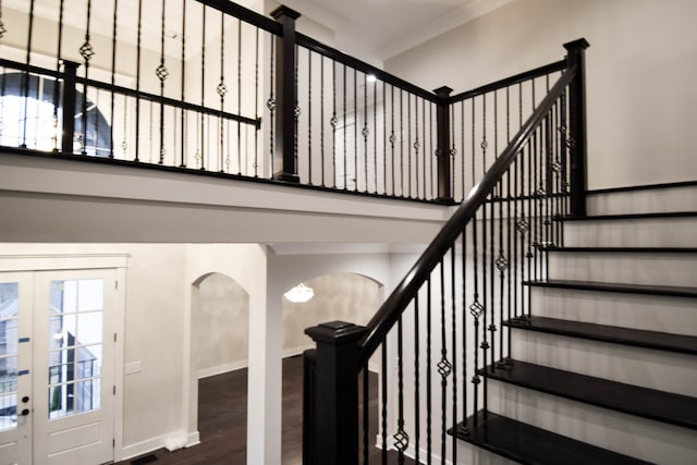 stairs featuring baseboards, arched walkways, wood finished floors, and french doors