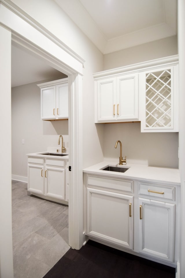 bar with ornamental molding, indoor wet bar, a sink, and baseboards