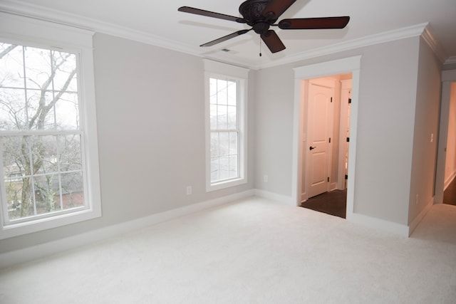 carpeted empty room with a wealth of natural light, baseboards, and crown molding