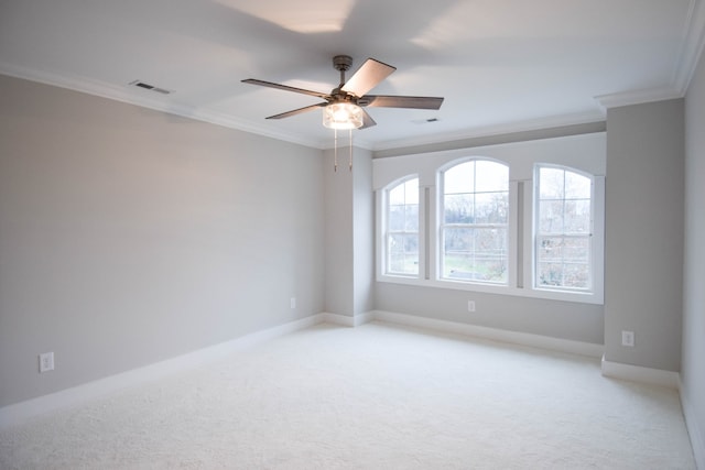 spare room with ceiling fan, light carpet, visible vents, baseboards, and crown molding