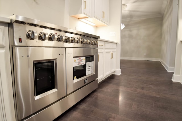 kitchen with baseboards, range with two ovens, dark wood finished floors, ornamental molding, and white cabinetry