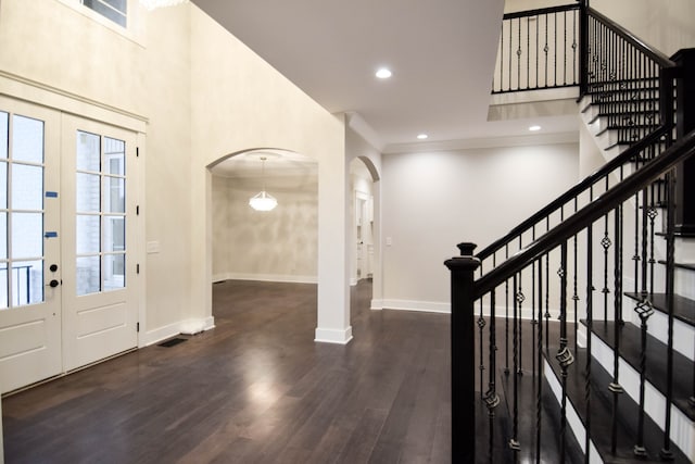 entrance foyer with baseboards, arched walkways, wood finished floors, and french doors