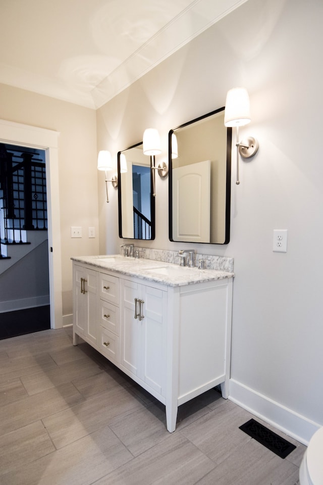 bathroom with wood finished floors, a sink, visible vents, baseboards, and double vanity