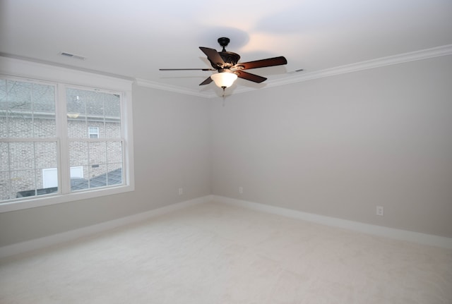 carpeted spare room featuring baseboards, a ceiling fan, visible vents, and crown molding