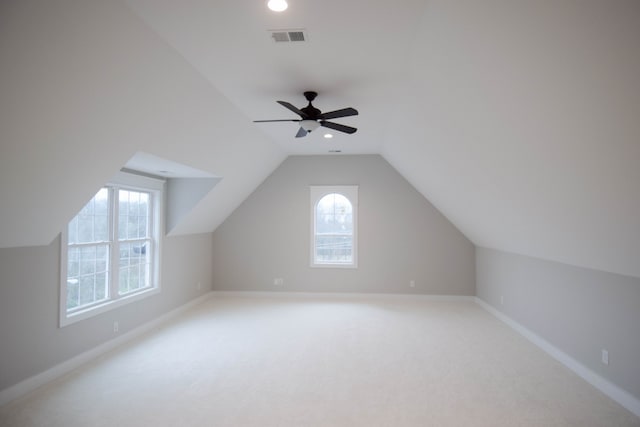 bonus room featuring light colored carpet, visible vents, lofted ceiling, and baseboards