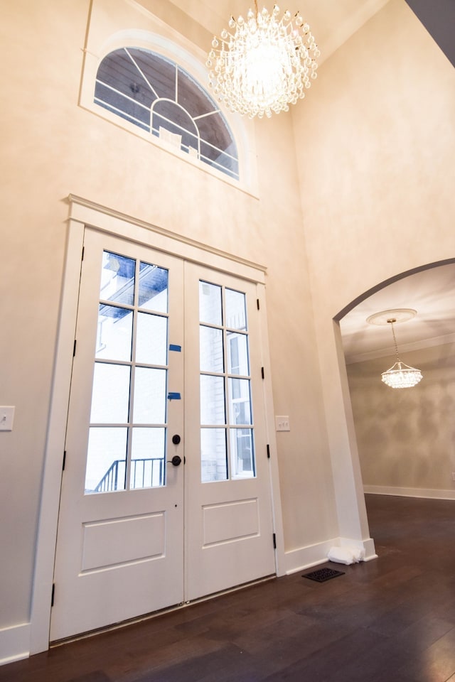 entryway with arched walkways, french doors, baseboards, and wood finished floors