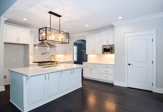 kitchen with arched walkways, stainless steel appliances, crown molding, light countertops, and white cabinetry