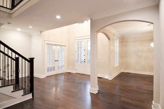 foyer with arched walkways, french doors, stairway, and wood finished floors