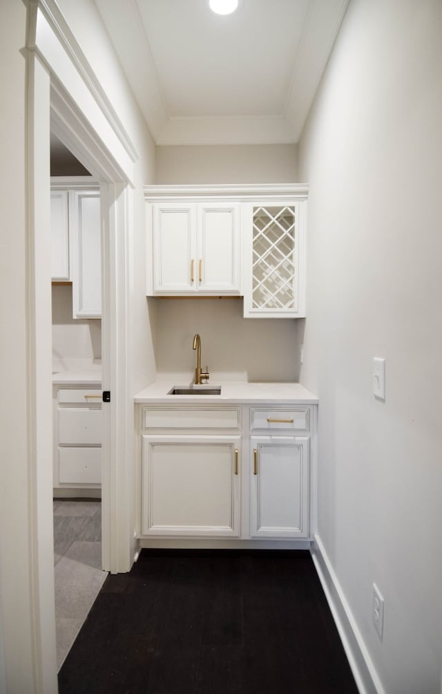 bar featuring ornamental molding, a sink, and baseboards