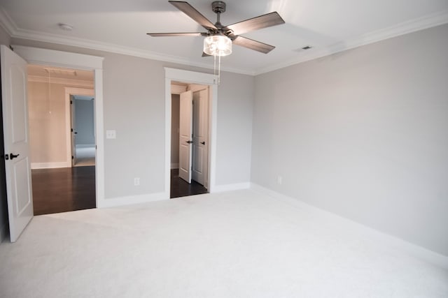 unfurnished bedroom featuring crown molding, visible vents, carpet flooring, ceiling fan, and baseboards