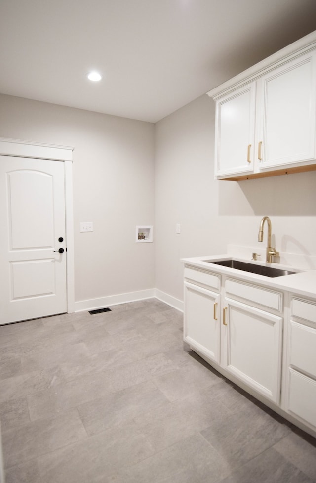 laundry room featuring cabinet space, hookup for a washing machine, baseboards, and a sink