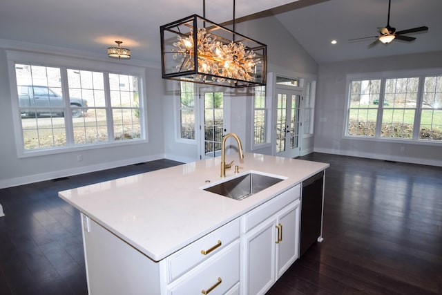 kitchen featuring light countertops, open floor plan, vaulted ceiling, a sink, and dishwasher