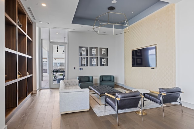 living room with hardwood / wood-style flooring and a tray ceiling