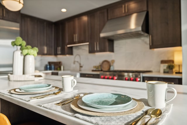 kitchen with dark brown cabinets, decorative backsplash, stove, and sink