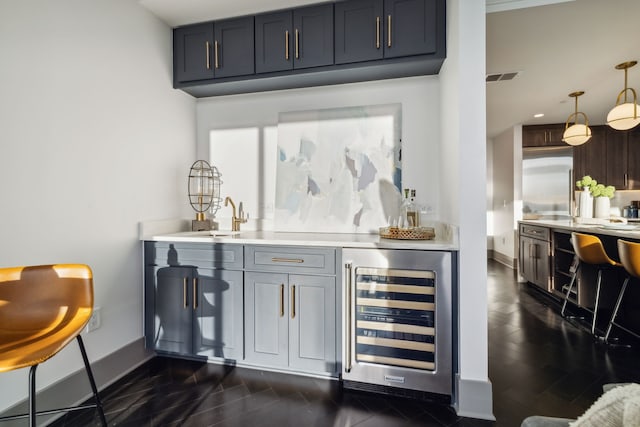 bar featuring wine cooler, pendant lighting, and sink