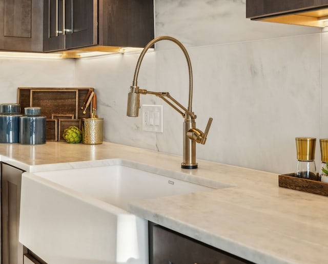 kitchen with light stone countertops, sink, and dark brown cabinetry