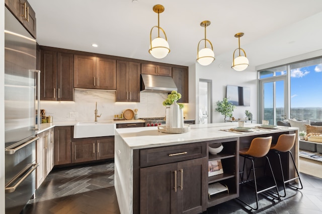 kitchen featuring dark brown cabinetry, sink, decorative light fixtures, and built in refrigerator