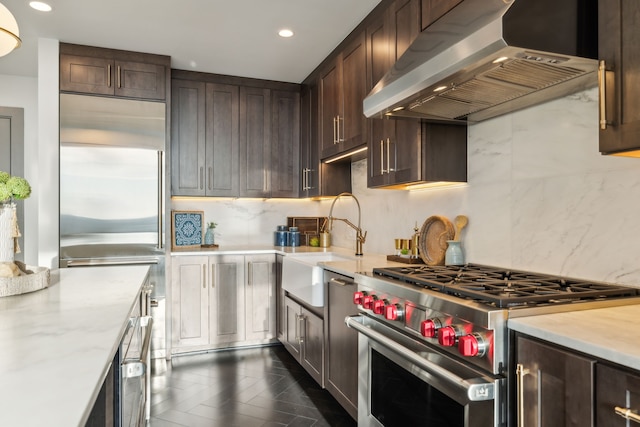 kitchen with dark brown cabinets, high quality appliances, decorative backsplash, and exhaust hood