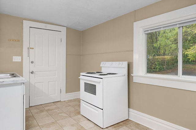 kitchen with electric stove, light tile patterned flooring, and white cabinets