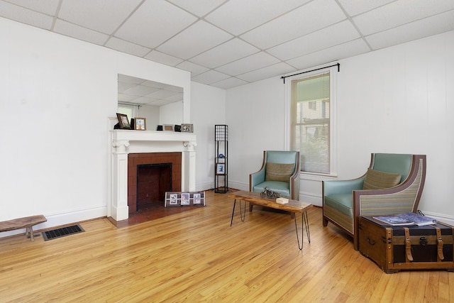 sitting room featuring a fireplace, a paneled ceiling, and wood-type flooring