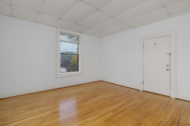 spare room with light hardwood / wood-style flooring and a paneled ceiling