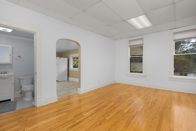 spare room with light wood-type flooring, sink, and a healthy amount of sunlight