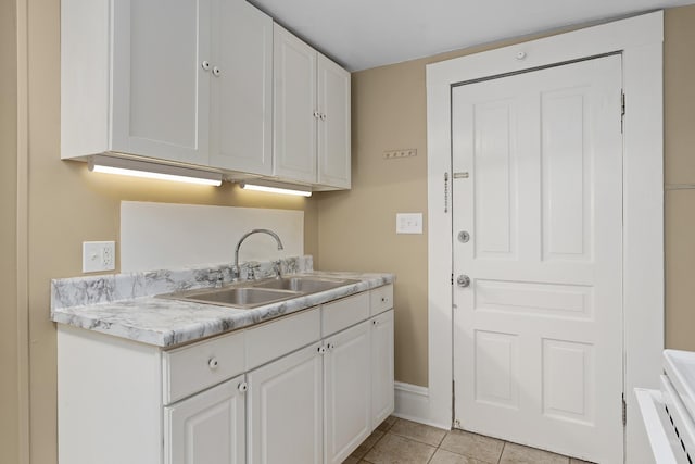 kitchen with white cabinets, light tile patterned floors, and sink