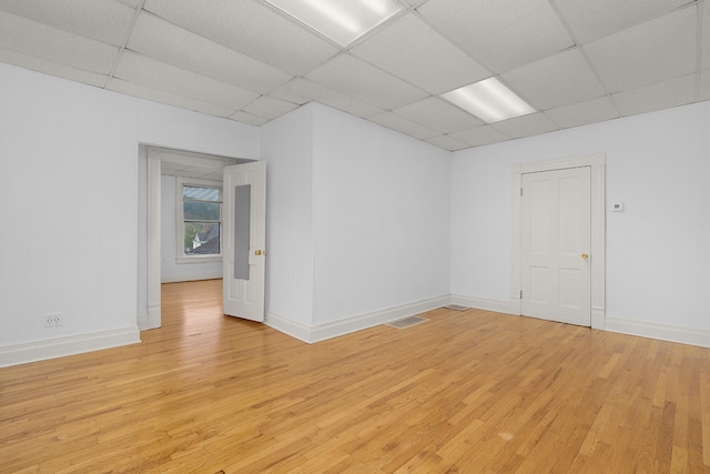 unfurnished room with a drop ceiling and light hardwood / wood-style floors