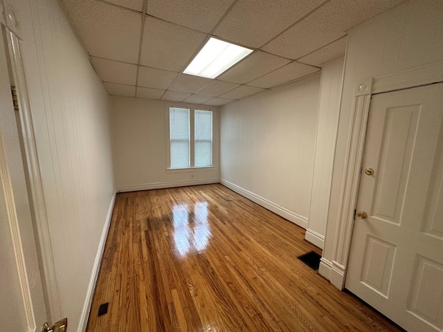 spare room featuring light hardwood / wood-style flooring and a drop ceiling