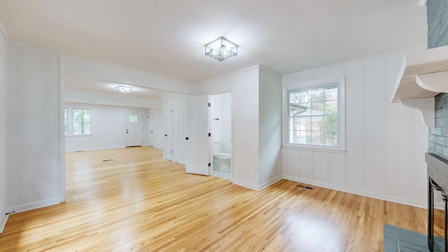 unfurnished living room featuring light hardwood / wood-style floors and a brick fireplace