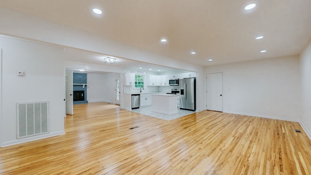 kitchen featuring light hardwood / wood-style floors, decorative backsplash, sink, white cabinetry, and appliances with stainless steel finishes