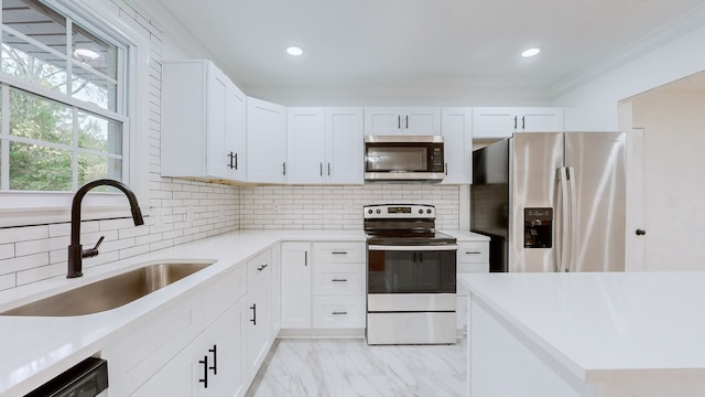 kitchen with white cabinetry, sink, appliances with stainless steel finishes, tasteful backsplash, and crown molding