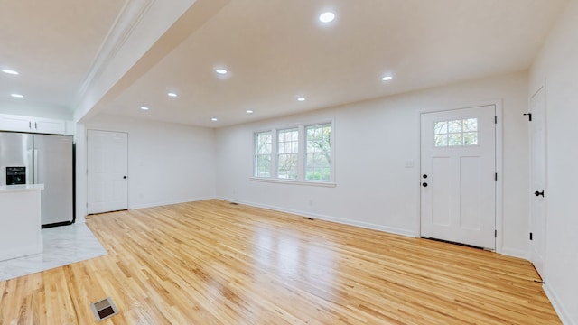 unfurnished living room featuring light wood-type flooring and ornamental molding