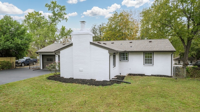 back of house featuring a garage and a yard