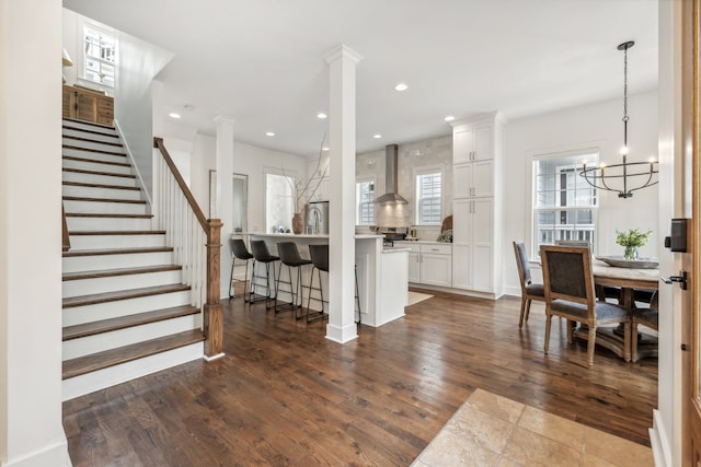 interior space featuring ornate columns, dark hardwood / wood-style floors, and an inviting chandelier