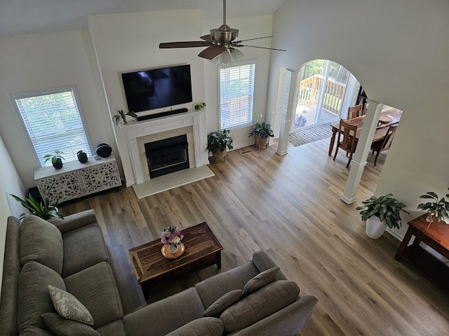 living room with high vaulted ceiling, a tile fireplace, hardwood / wood-style flooring, and ceiling fan