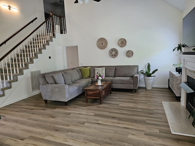 living room featuring wood-type flooring, ceiling fan, and a high ceiling