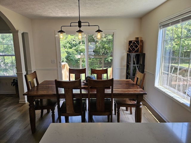 dining space with dark wood-type flooring, a wealth of natural light, and a textured ceiling