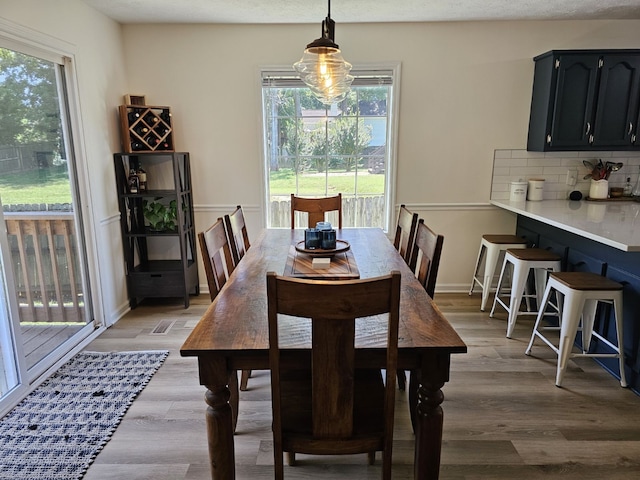 dining space featuring light wood-type flooring, a wealth of natural light, and a textured ceiling