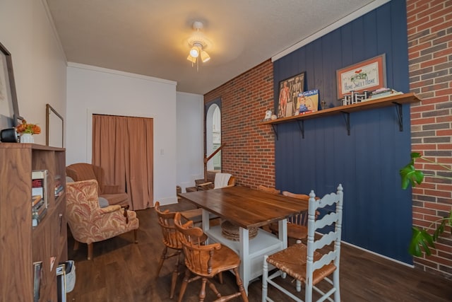 dining room with brick wall, ceiling fan, dark hardwood / wood-style floors, crown molding, and wooden walls