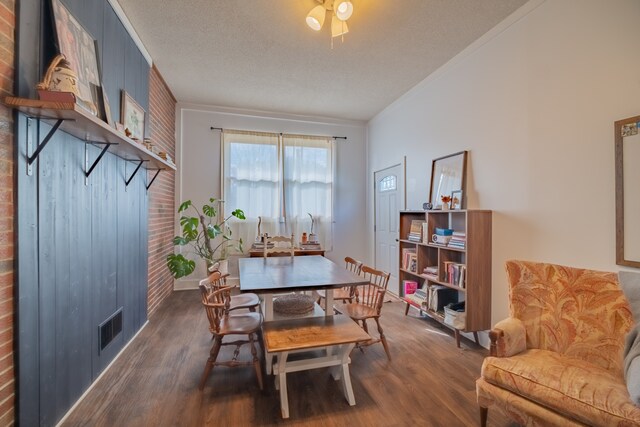 dining space featuring a textured ceiling, brick wall, dark hardwood / wood-style floors, and crown molding