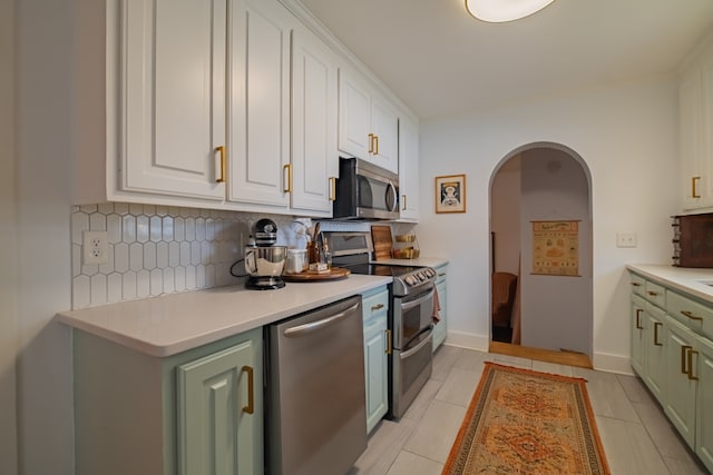 kitchen featuring white cabinetry, appliances with stainless steel finishes, light tile patterned flooring, and backsplash