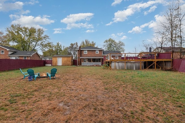 view of yard featuring a deck, a storage unit, and an outdoor fire pit